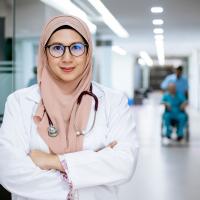 Female doctor in a white coat and a peach head scarf
